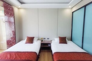Habitación de hotel con dos camas, una mesita de noche y un ventanal grande.