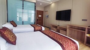 Una habitación de hotel con dos camas, un televisor y un armario de madera.