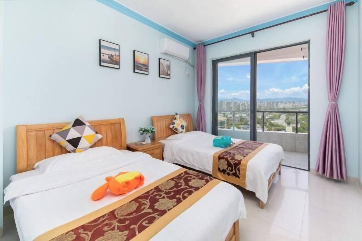 Une chambre d’hôtel avec deux lits, une grande fenêtre donnant sur la ville et un balcon.