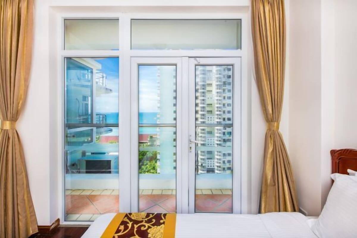 Une chambre d’hôtel avec un balcon, un lit et des rideaux.