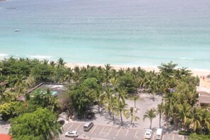 A beachfront property with a parking lot, palm trees, and a view of the ocean. - Sanya Hai Hua Apartment (Sanya)