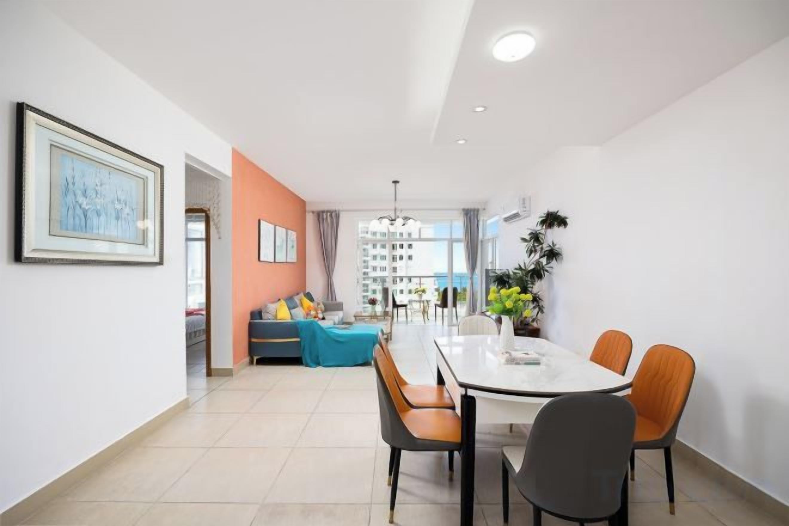 A modern dining area with a white table and chairs, a sofa with cushions, and a view of a building in the background.