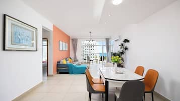 A modern dining area with a white table and chairs, a sofa with cushions, and a view of a building in the background.