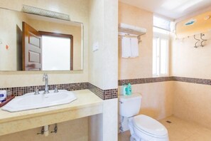 A bathroom with a sink, mirror, toilet, and shower area. - Sanya Hai Hua Apartment (Sanya)