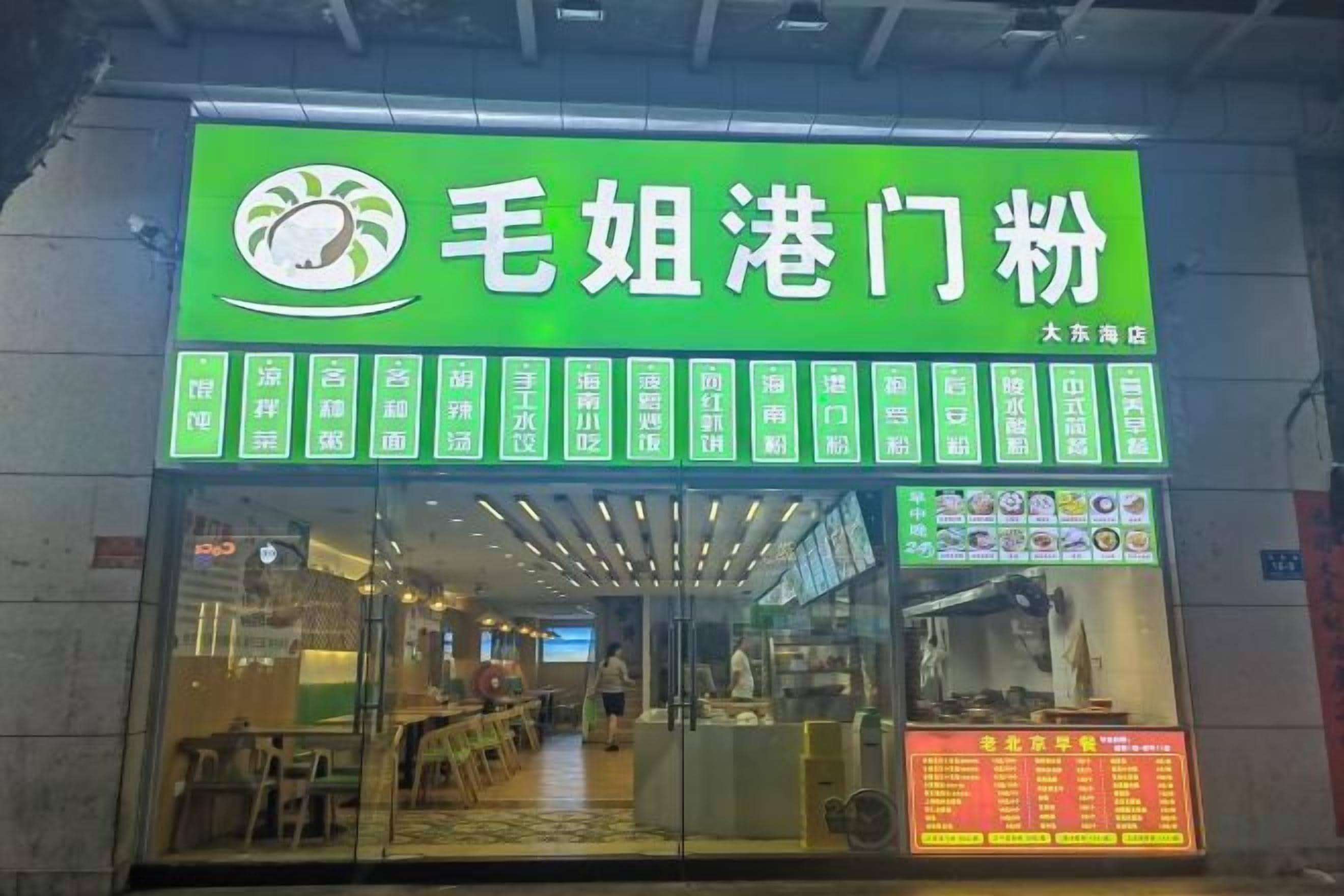 A restaurant with a green signboard displaying its name and menu.