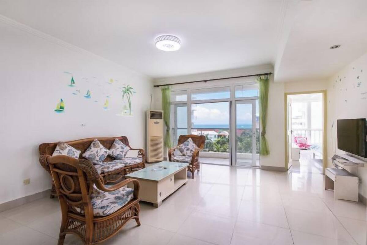 Un salon comprenant un canapé, une table basse, un téléviseur et un balcon avec vue.