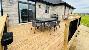 A house with a stone exterior, a deck with a table and chairs, and a barbecue grill. - 3 mins drive to Beach |5 bdrm|Sleeps 18 (Port Elgin)