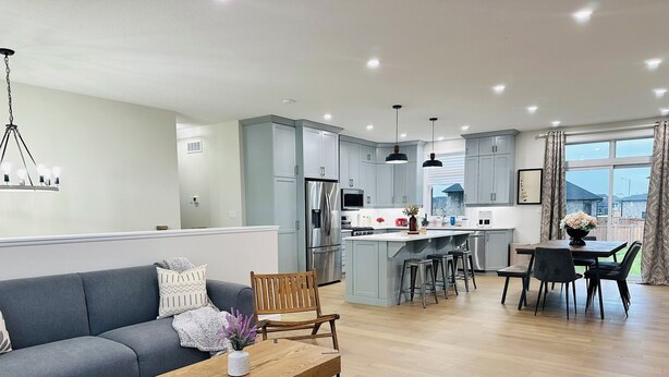 A modern kitchen with grey cabinets, a central island, and bar stools. - 3 mins drive to Beach |5 bdrm|Sleeps 18 (Port Elgin)
