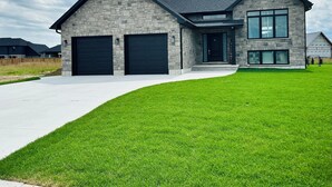 A modern two-story house with a stone facade, two garage doors, and a well-maintained lawn. - 3 mins drive to Beach |5 bdrm|Sleeps 18 (Port Elgin)