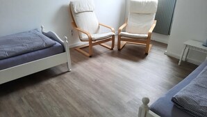 A room with two single beds, a wooden chair, and a small table. - Neue und Ruhig Gelegene Ferienwohnung am Wittensee und in den Hüttener Bergen (Klein Wittensee)