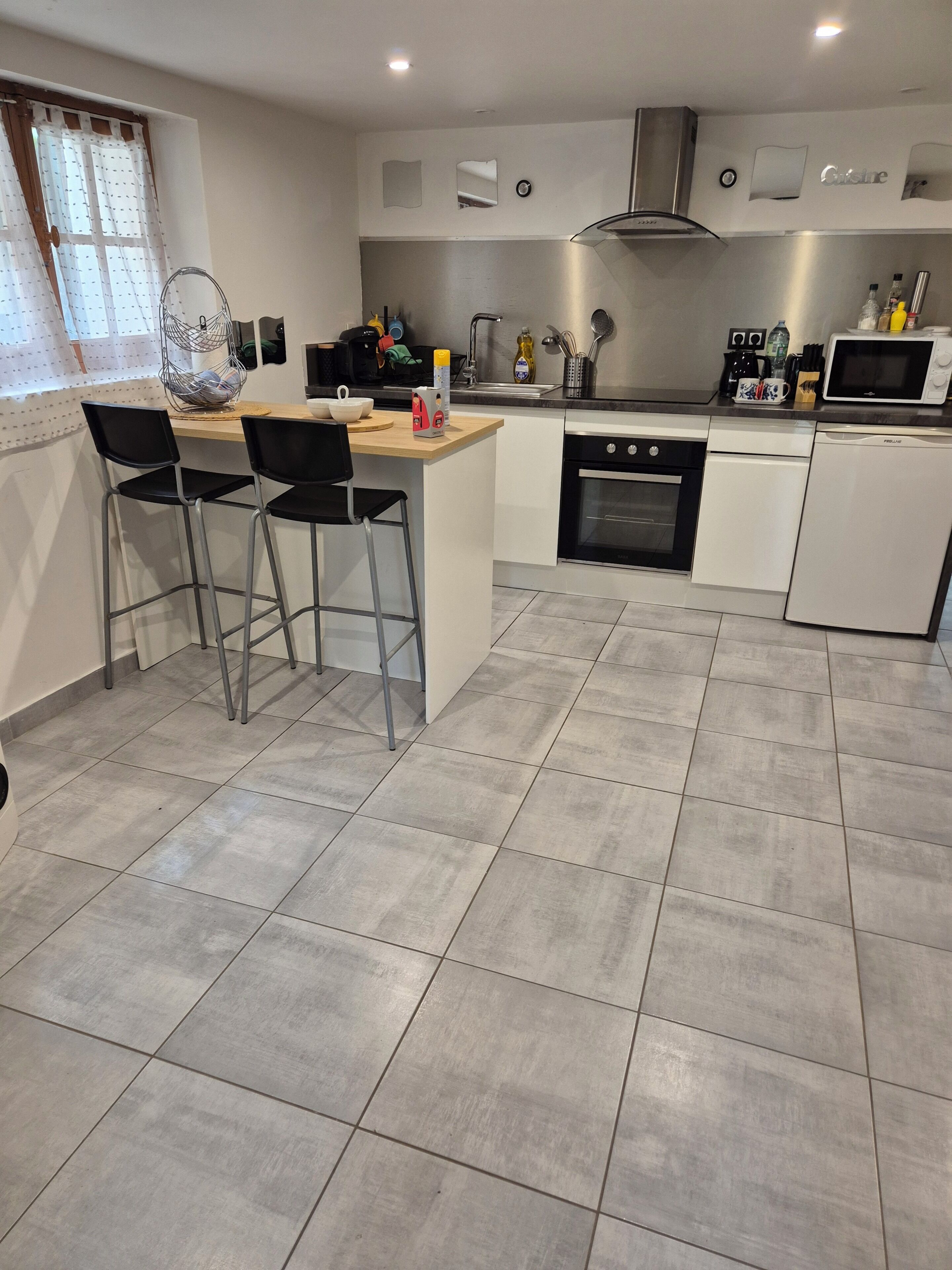 Een moderne keuken met een centraal eiland, barstoelen, een magnetron en een vaatwasser.