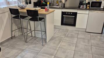 Een moderne keuken met een centraal eiland, barstoelen, een magnetron en een vaatwasser.