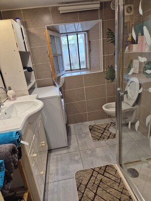 Ein Badezimmer mit Waschbecken, Toilette, Dusche und einem Fenster.