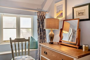 A room with a wooden dresser, a lamp, a mirror, a chair, a window with curtains, and framed pictures on the wall. - 2 Bed in Frogmore (oc-s29476) (Frogmore)