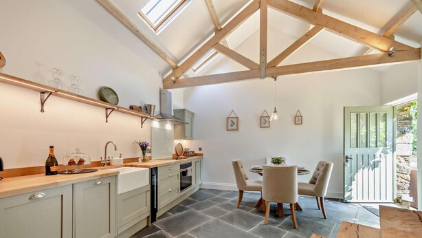A kitchen with a dining area, wooden beams, and a view of the outside.
