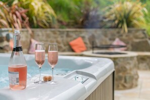 A hot tub with a bottle of pink drink and two glasses on the edge. - 2 Bed in Kelly (oc-k29333) (Kelly)