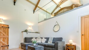 A modern living room with a grey sofa, a wooden bench, a small table, and a mirror on the wall.