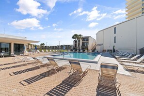 A pool area with sun loungers and a clear sky.