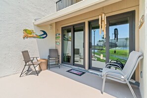 A balcony with two chairs, a wicker chair, and a small table.