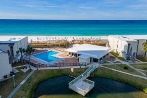 A resort with a swimming pool, a covered outdoor area, and a view of the beach.
