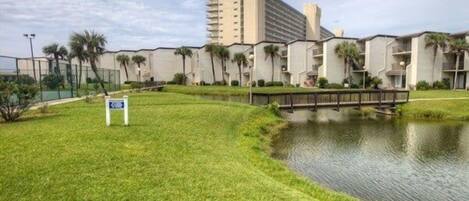 Um hotel com área gramada, lago e ponte.