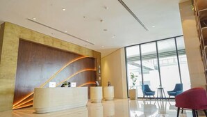 A modern reception area with a curved reception desk, a large window offering a view of the outside, and a seating area with chairs.
