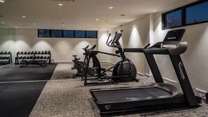 A gym with treadmills, elliptical machines, and dumbbells.