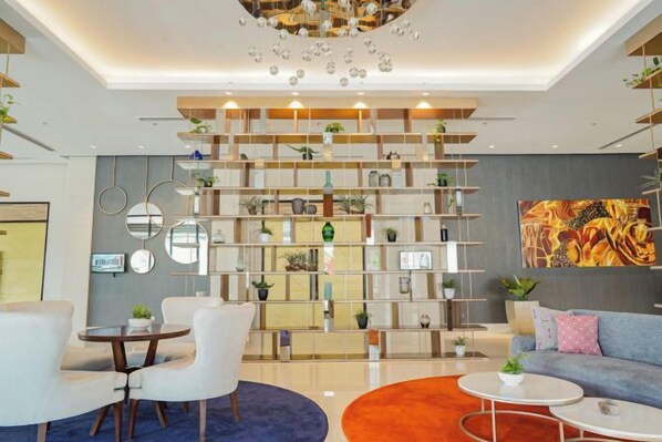 A modern interior with a central shelving unit, seating area, and a chandelier.