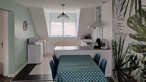 Una cocina moderna con zona de comedor, que cuenta con un amplio ventanal, una lámpara colgante y una isla de cocina.