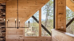 Un interior de madera con un candelabro, ventanas amplias y una pared de piedra.
