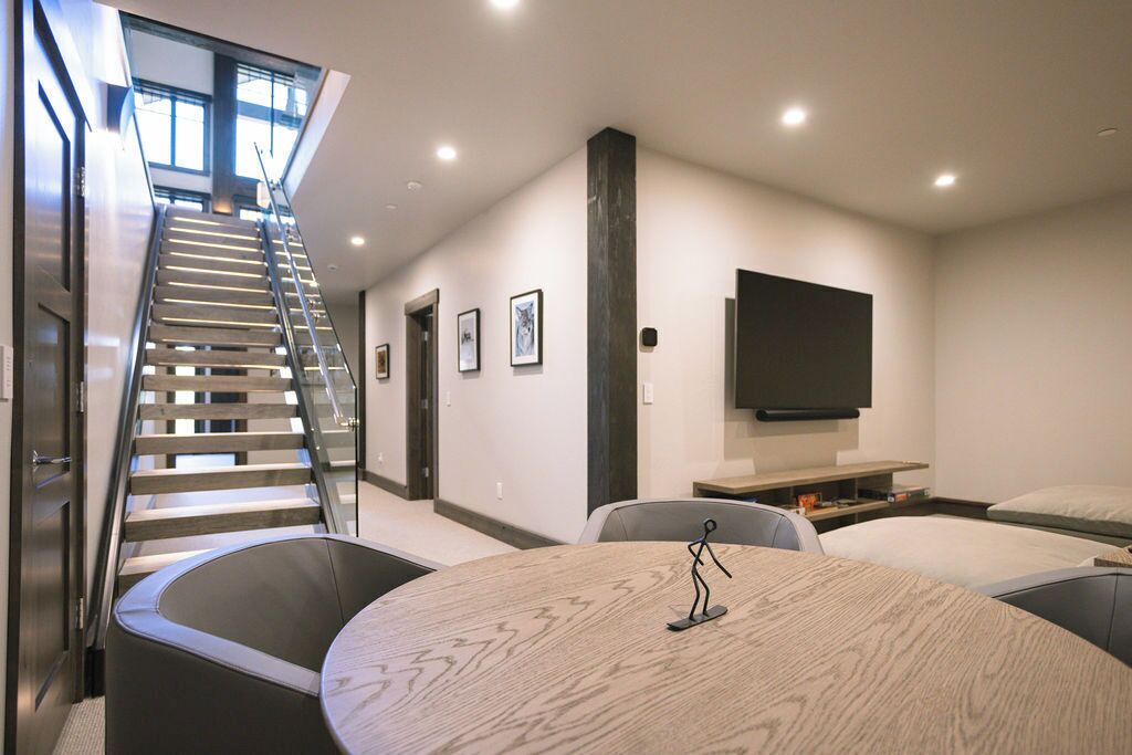 Habitación de hotel moderna con una escalera, una mesa redonda para comer, un televisor y una cama.