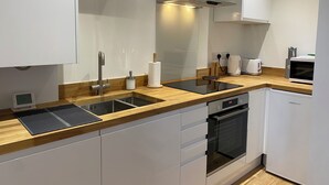 A modern kitchen with white cabinets, a stainless steel sink, a built-in oven, and a microwave. - The Matcham Studio in the heart of Buxton (Buxton)