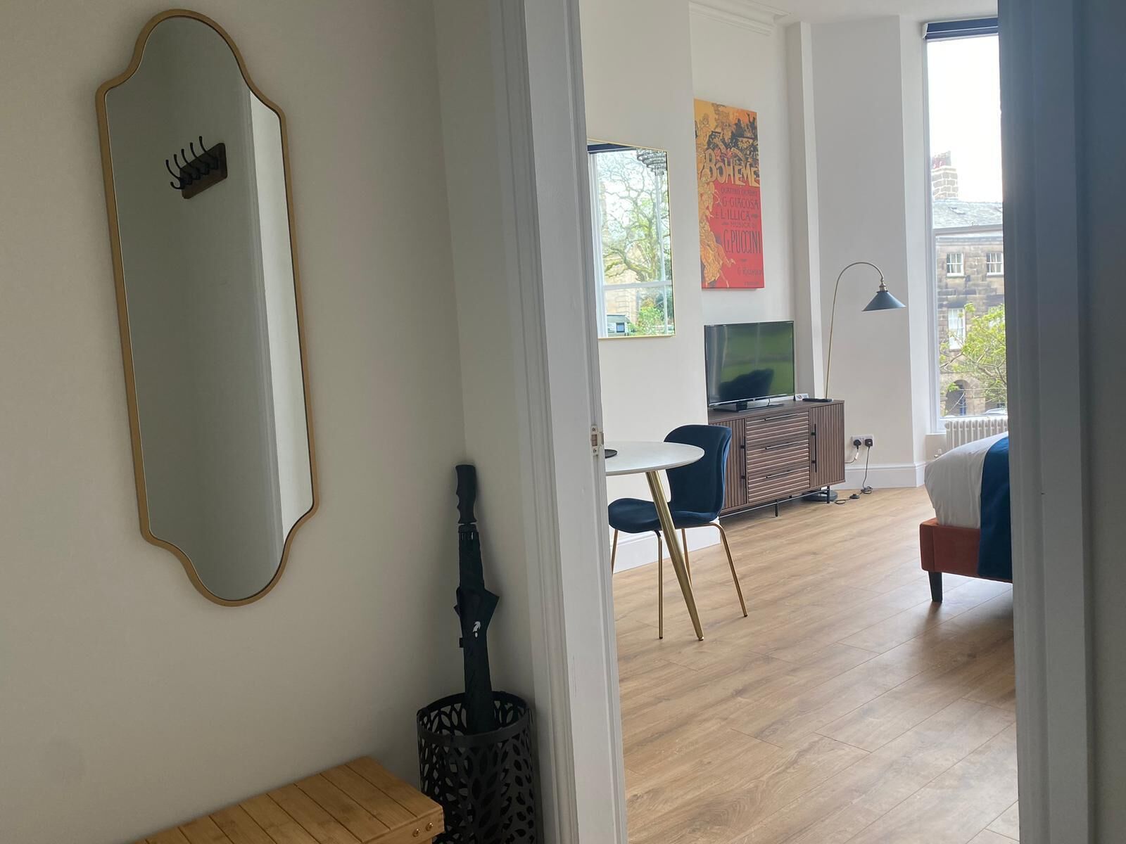 Una sala de estar moderna con un espejo grande, un televisor y un comedor con mesa y sillas.
