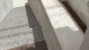 A narrow, stone-walled stairwell with a metal railing and a small opening at the top. - Comfortable Stay (Amman)