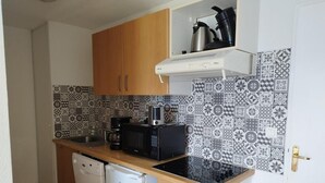 Een kleine keuken met een magnetron, koffiezetapparaat en vaatwasser.
