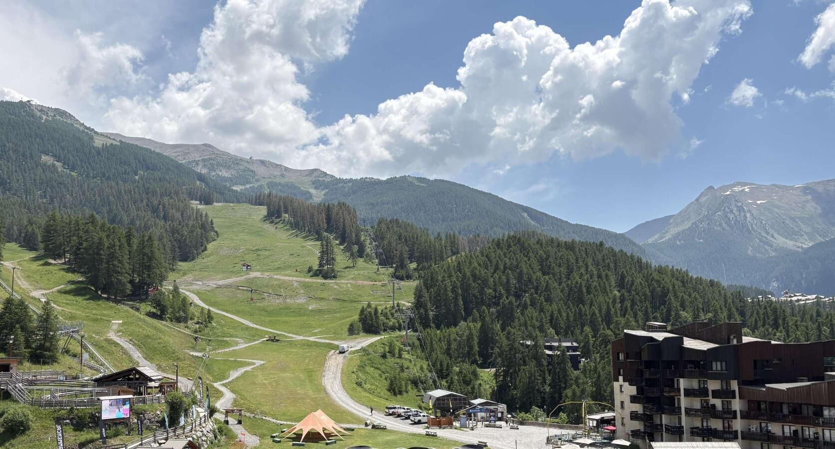 A mountainous landscape with a ski resort, including a ski lift, buildings, and a road.