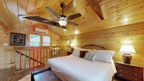 Un dormitorio acogedor con techo de madera, una cama con ropa de cama blanca, dos mesitas de noche con lámparas y un ventilador de techo.