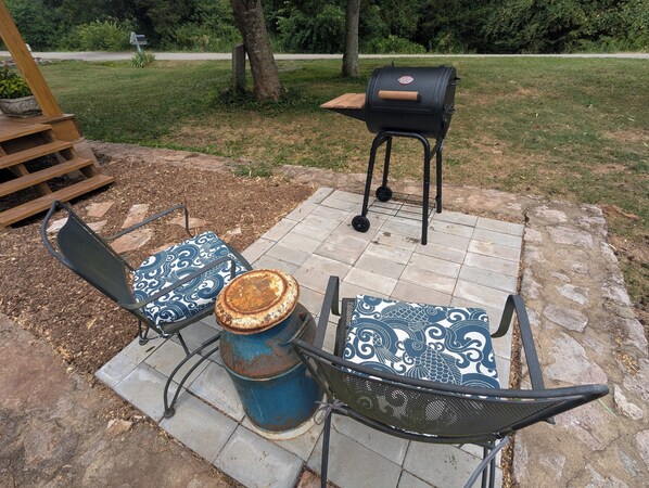 Un patio con dos sillas de metal y un barril azul.