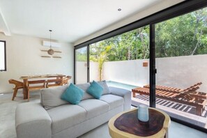 Relax in this serene living space with a sofa by the window, a dining table, and a unique coffee table.
