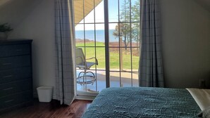 A bedroom with a bed, a dresser, a chair, and a view of the outdoors through a sliding glass door. - On one of the 𝗜𝘀𝗹𝗮𝗻𝗱'𝘀 𝗯𝗲𝘀𝘁 𝗯𝗲𝗮𝗰𝗵𝗲𝘀; enjoy sun, sand & sea! (Bedeque)