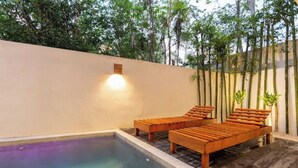 Un espace aménagé au bord de la piscine, avec des chaises longues en bois et une petite lampe fixée au mur.