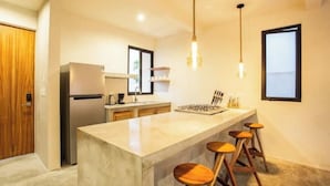 Une cuisine moderne dotée d’un îlot central, de tabourets de bar et de luminaires suspendus.