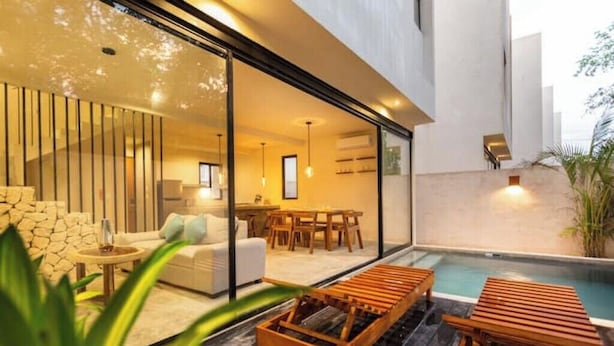 Un intérieur moderne comprenant un coin repas, un salon avec un canapé et une table basse, ainsi qu’un espace détente aménagé au bord de la piscine.