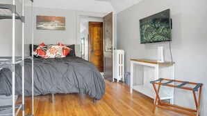 Un dormitorio con una cama, un radiador, un televisor y un banco de madera.