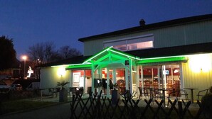 A building with a green-lit entrance and outdoor seating area. - Fasthôtel Albertville (Albertville)