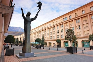 Une place publique avec une statue, un grand bâtiment doté de nombreuses fenêtres et un ciel dégagé.