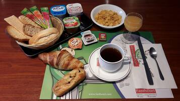 A breakfast setting with bread, pastries, yogurt, cereal, and a cup of coffee on a table with a placemat.