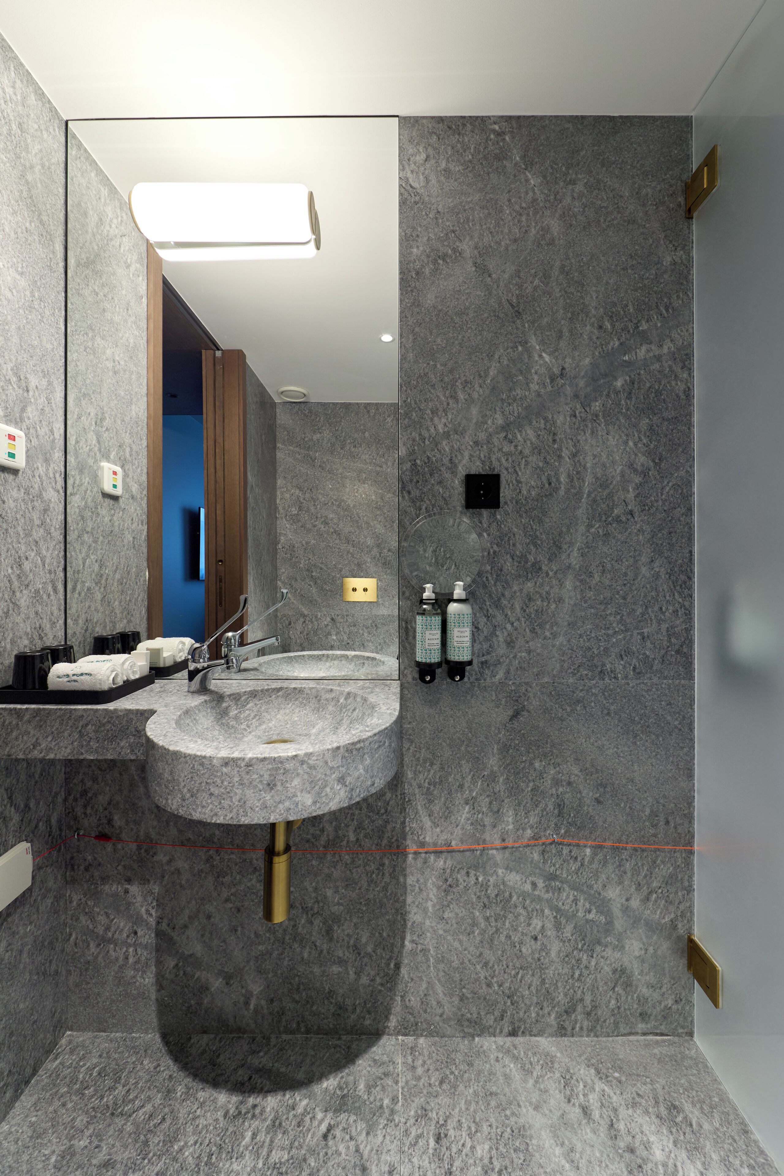 Un baño moderno con un lavamanos grande, un espejo y dos botellas de desinfectante de manos.