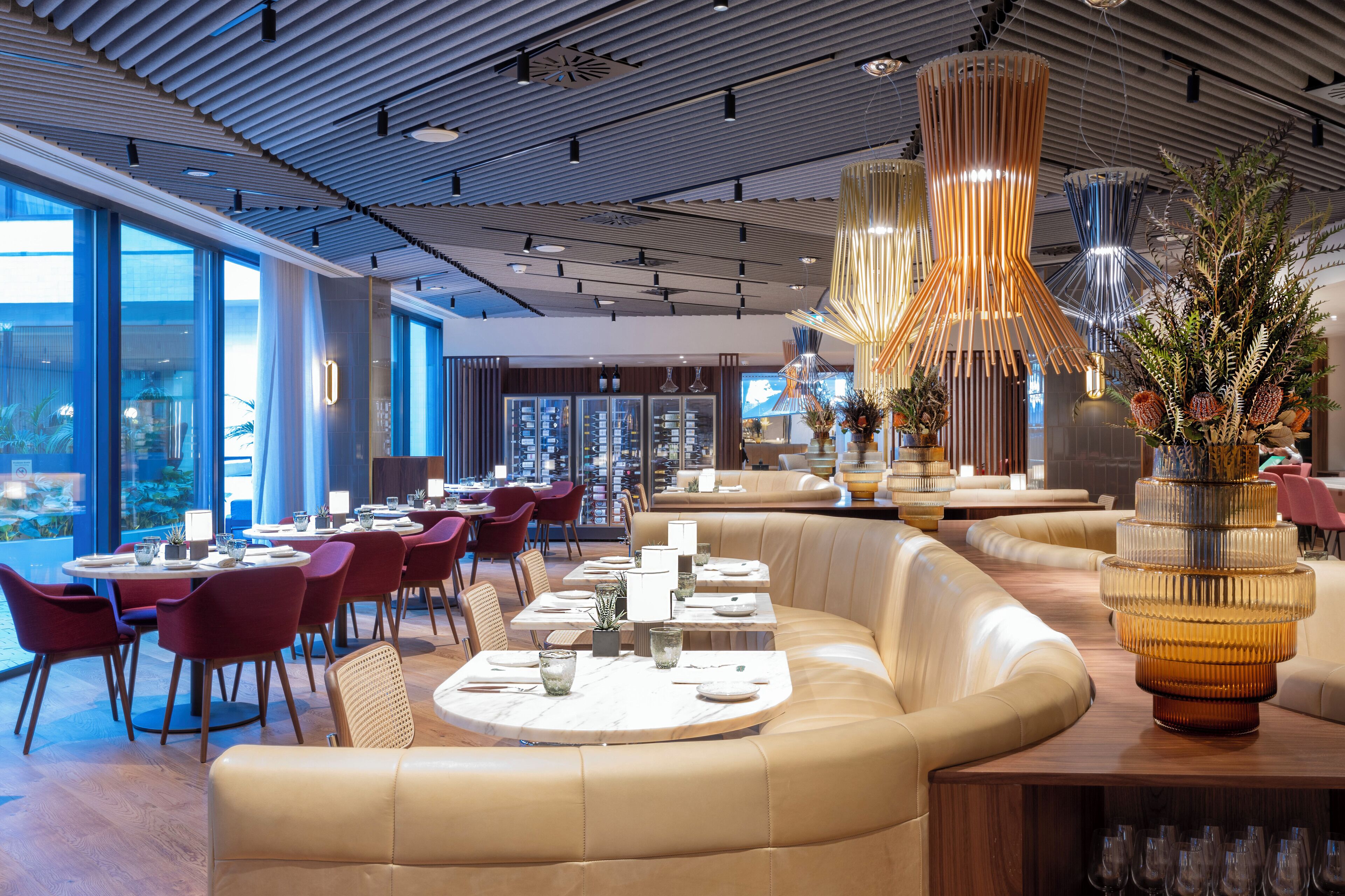 A modern restaurant with round tables, leather seating, and decorative lighting.