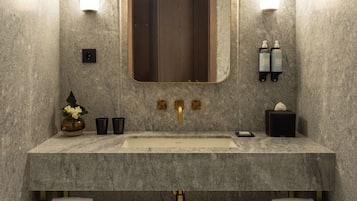 Uma casa de banho moderna com lavatório de mármore, um espelho grande, luzes embutidas, um porta-toalhas e uma balança.